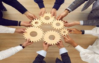 Profesionistas en circulo sosteniendo engranes en sus manos